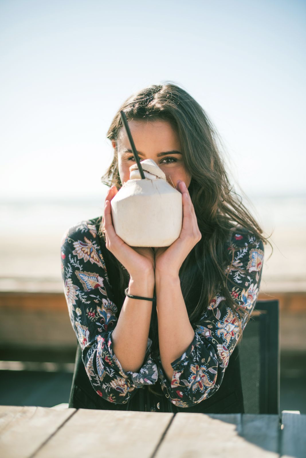 Woman drinking from a fresh young CocoBomb coconut on the beach