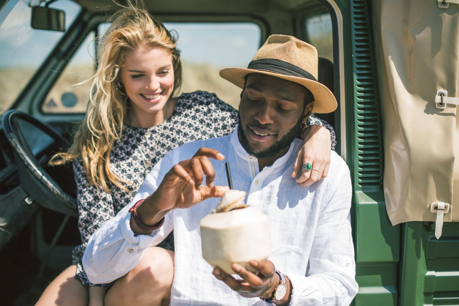 Couple opening a CocoBomb coconut in a van at the dunes